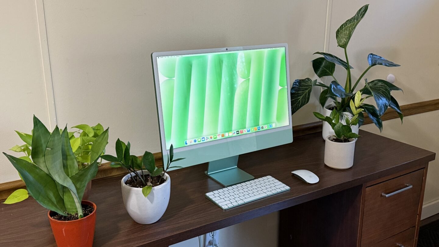 Green iMac with desk plants Green iMac sitting on a brown desk with various potted plants around it